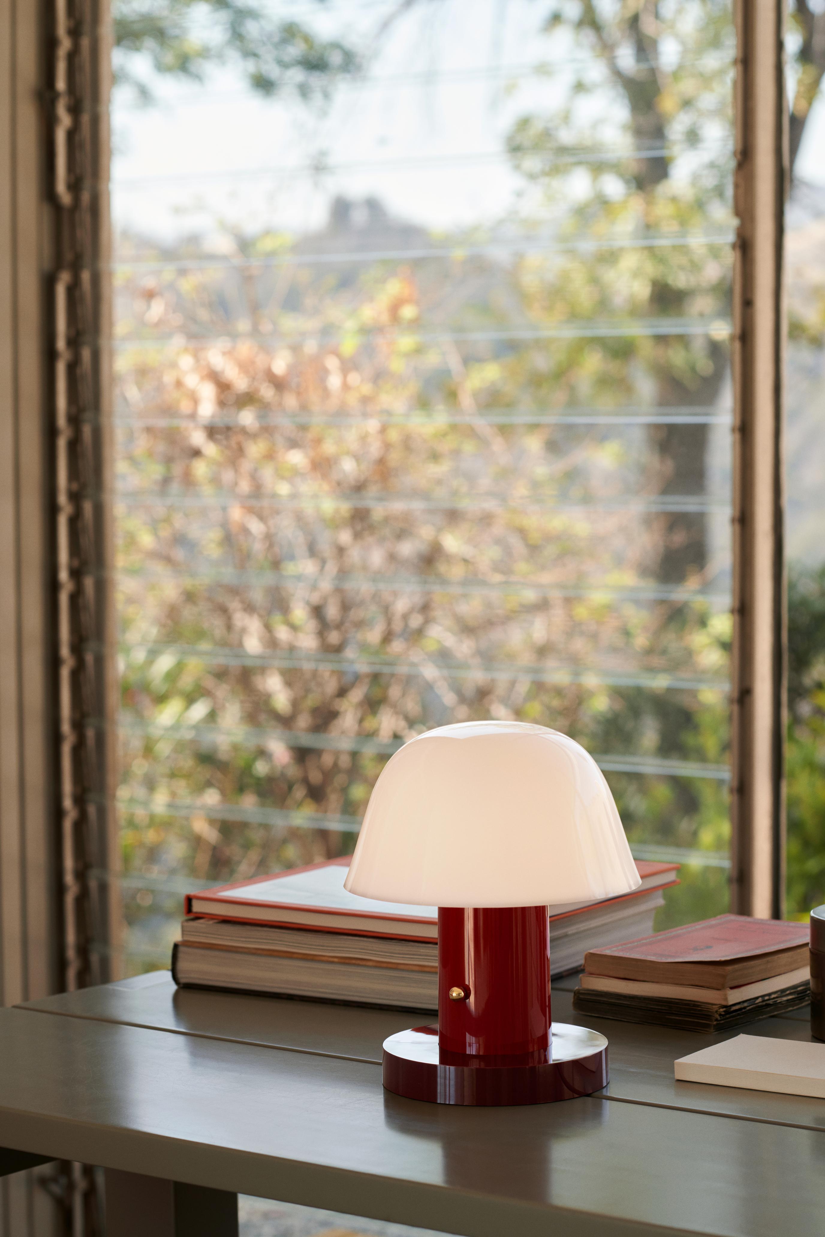 Draagbare lamp SETAGO JH27 met een crèmekleurige kap en een donkerrode voet.