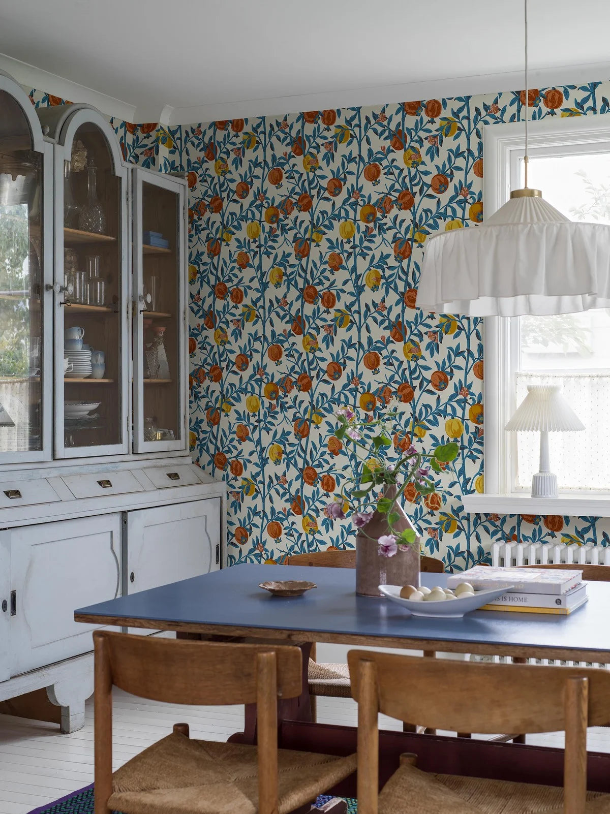 Behang met een plantaardig patroon van granaatappelvruchten wit met blauw en oranje